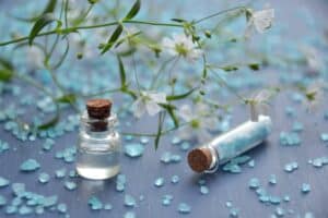 Pure Dead Sea mineral extract in glass bottles with delicate white flowers and blue mineral flakes, showcasing Dead Sea cosmetics and natural skincare ingredients.