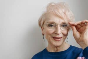 Luxurious older woman with clear skin and stylish glasses natural beauty, showcasing skincare with Dead Sea mineral products for anti-aging and rejuvenation.
