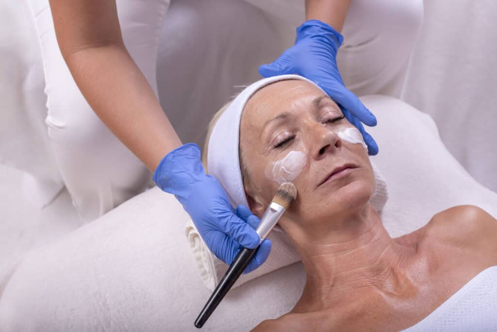 senior woman applying face cream in a beauty salon