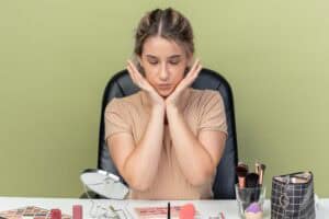 Smiling young woman at desk with makeup tools, representing beauty routine and skin care focus
