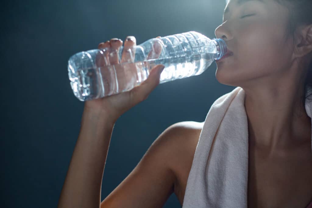 Women after exercise drink water from bottles and handkerchiefs in the gym
